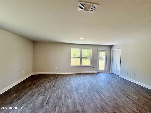 empty room featuring baseboards, dark wood-style floors, and visible vents