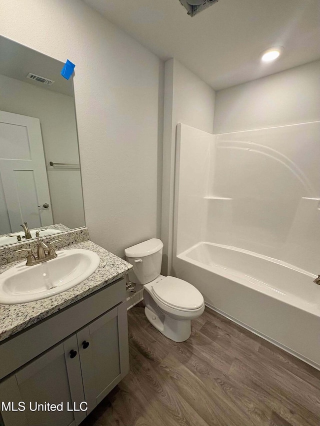 full bath with vanity, shower / tub combination, toilet, visible vents, and wood finished floors