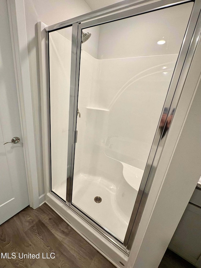 full bath with a shower stall and wood finished floors