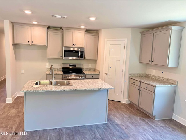 kitchen with light wood-style flooring, a sink, baseboards, and stainless steel appliances