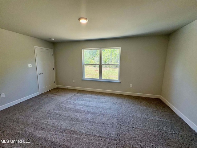 empty room featuring baseboards and dark colored carpet