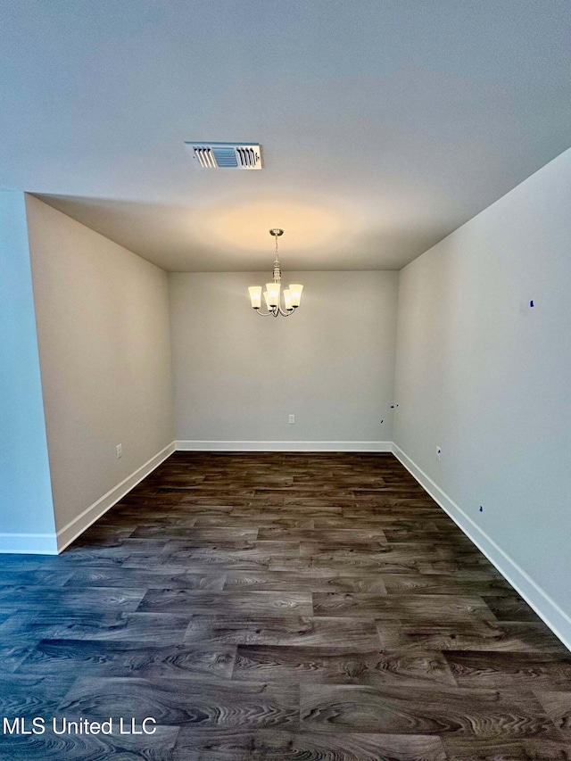 unfurnished dining area with baseboards, a notable chandelier, dark wood finished floors, and visible vents