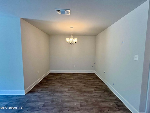 unfurnished dining area featuring dark wood-style flooring, visible vents, baseboards, and a chandelier