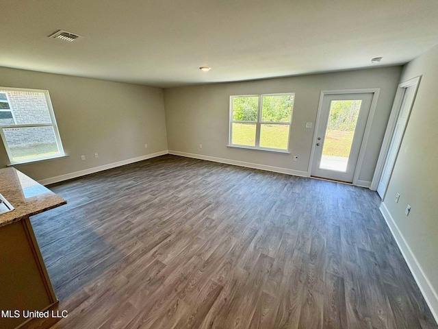 unfurnished living room featuring dark wood-type flooring, visible vents, and baseboards