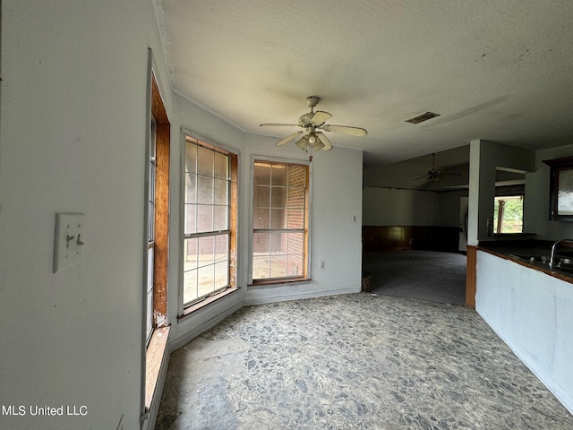 unfurnished dining area with ceiling fan, a textured ceiling, and a wealth of natural light