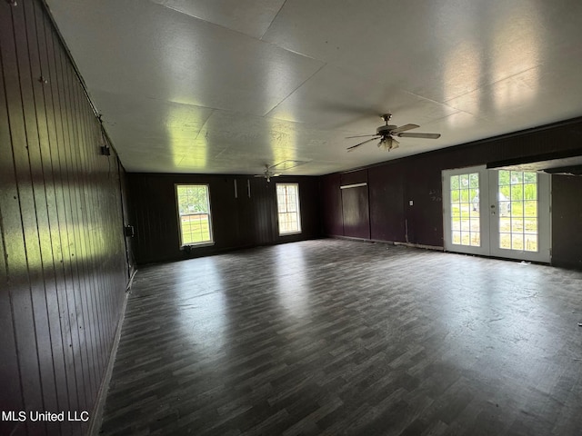 unfurnished room featuring ceiling fan, wood walls, and dark hardwood / wood-style floors