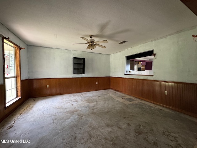 empty room featuring concrete floors, a textured ceiling, a healthy amount of sunlight, and ceiling fan