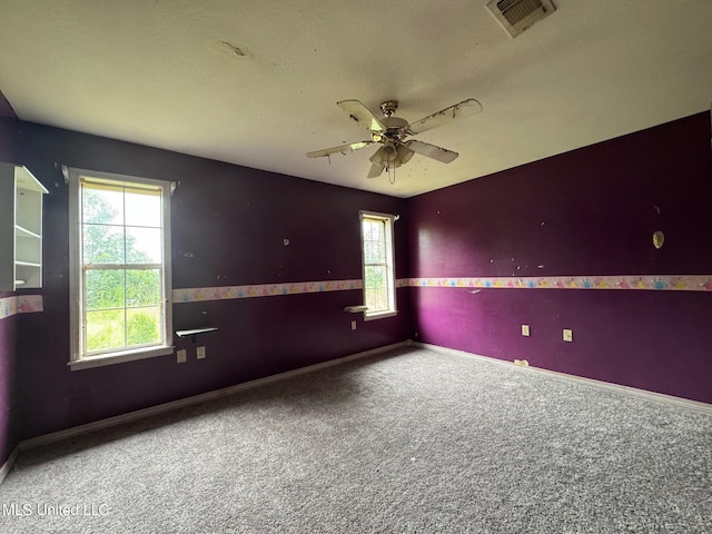 carpeted empty room featuring ceiling fan and a wealth of natural light