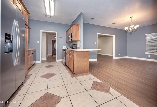 8002 Martin Bluff Rd, Gautier, MS 39553 - kitchen with appliances with stainless steel finishes, a peninsula, a chandelier, light tile patterned floors, and open floor plan