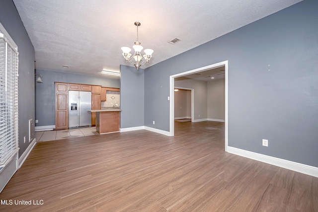 8002 Martin Bluff Rd, Gautier, MS 39553 - unfurnished living room with a chandelier, light wood-type flooring, and a textured ceiling