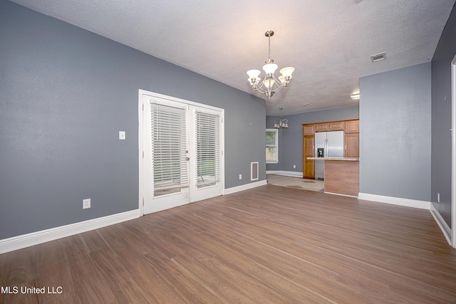 8002 Martin Bluff Rd, Gautier, MS 39553 - unfurnished living room featuring a chandelier, wood finished floors, french doors, and a textured ceiling