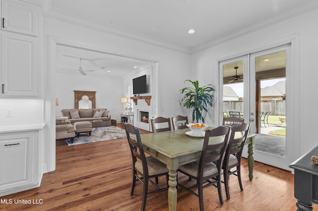 131 Camden Trl, Madison, MS 39110 - dining room featuring ceiling fan, ornamental molding, a warm lit fireplace, light wood-type flooring, and french doors