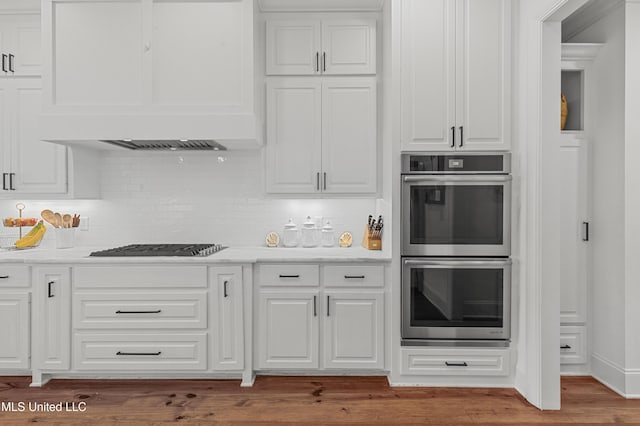 131 Camden Trl, Madison, MS 39110 - kitchen with stainless steel double oven, custom exhaust hood, white cabinetry, gas stovetop, and decorative backsplash