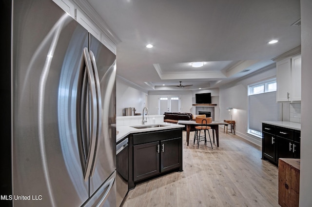 kitchen featuring sink, ceiling fan, stainless steel fridge, a tray ceiling, and white cabinetry