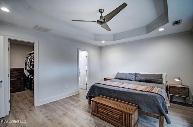 bedroom featuring ornamental molding, a raised ceiling, ceiling fan, a spacious closet, and a closet