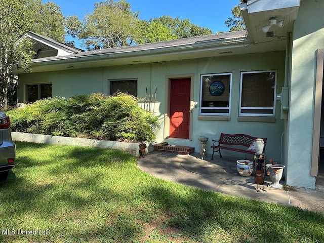 view of exterior entry featuring a patio area and a yard