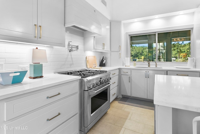 kitchen featuring white cabinets, decorative backsplash, light tile patterned floors, premium range hood, and stainless steel range