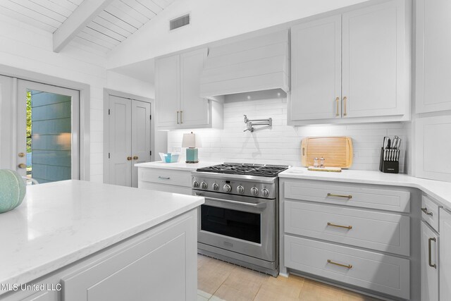 kitchen with high end stove, wood ceiling, lofted ceiling with beams, custom exhaust hood, and tasteful backsplash