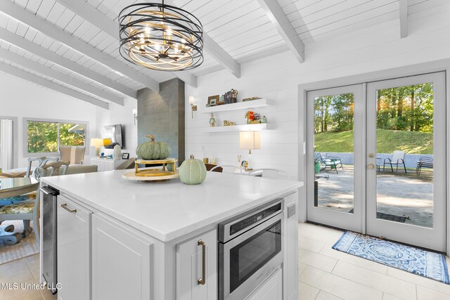 kitchen with light tile patterned flooring, vaulted ceiling with beams, french doors, white cabinets, and a chandelier