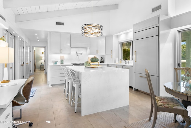 kitchen featuring white cabinetry, sink, decorative light fixtures, lofted ceiling with beams, and a center island