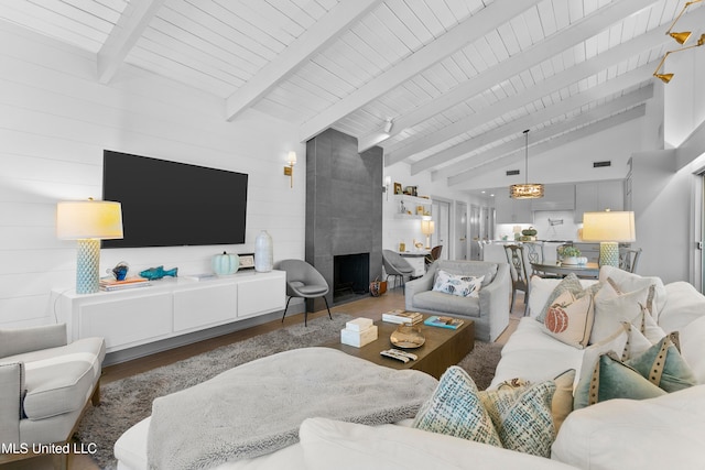 living room featuring wood ceiling, wood walls, dark wood-type flooring, a fireplace, and lofted ceiling with beams