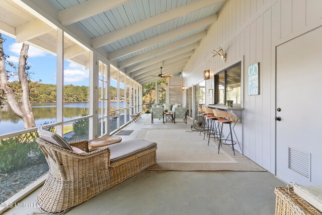 sunroom with a water view, ceiling fan, and vaulted ceiling with beams