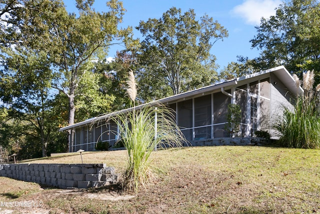 view of side of property featuring a lawn and a sunroom