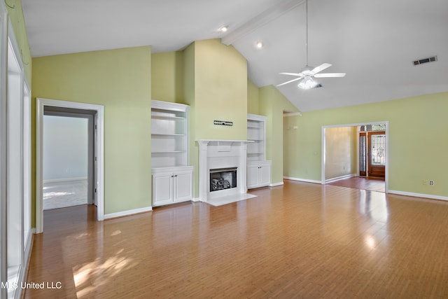 unfurnished living room with ceiling fan, beam ceiling, high vaulted ceiling, and hardwood / wood-style floors