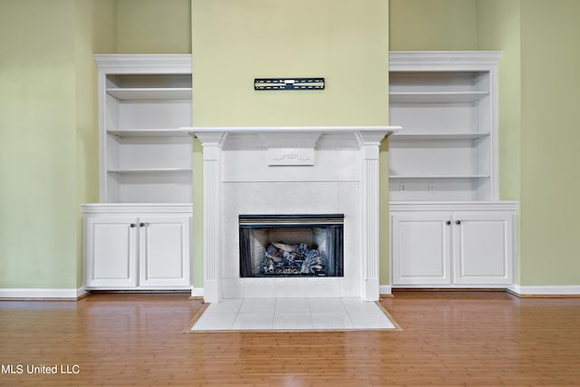 interior details with hardwood / wood-style flooring, a tiled fireplace, and built in features