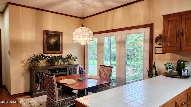 dining area with a wealth of natural light, ornamental molding, a notable chandelier, and hardwood / wood-style flooring