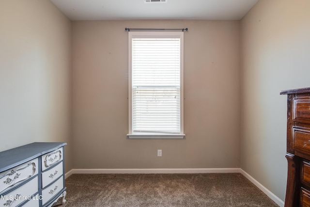 spare room featuring visible vents, dark colored carpet, and baseboards