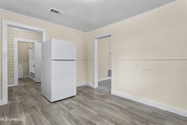 kitchen with white fridge, crown molding, and light hardwood / wood-style floors