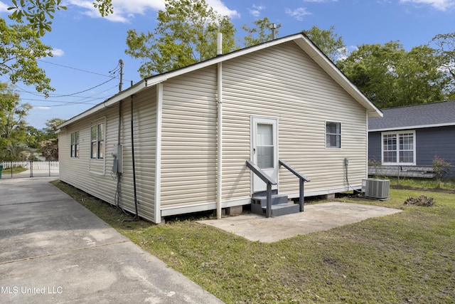 rear view of house with a lawn and central AC