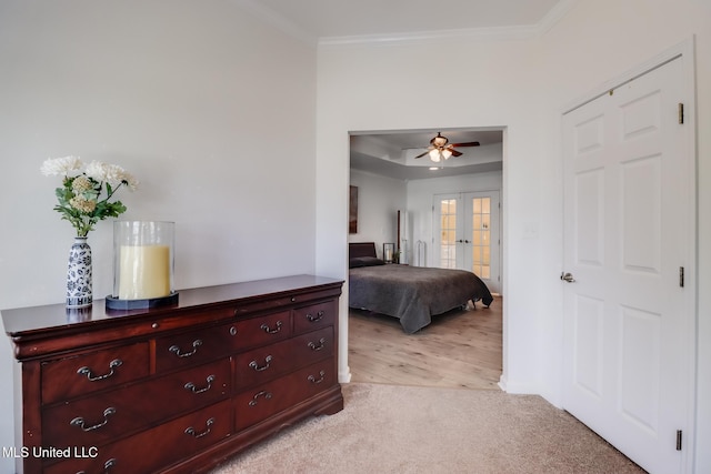 bedroom featuring crown molding, french doors, light colored carpet, and a tray ceiling