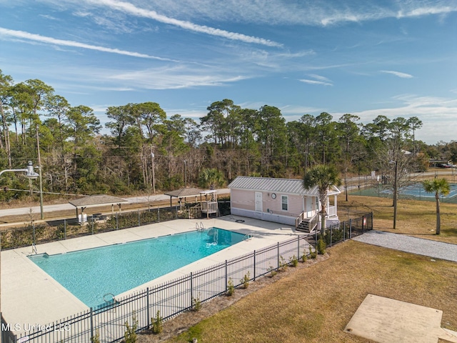 pool featuring a lawn, a patio, and fence