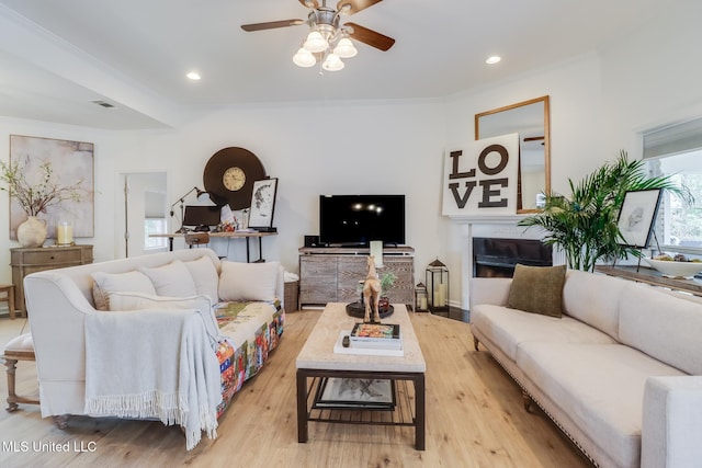 living area with visible vents, light wood-type flooring, crown molding, and ceiling fan