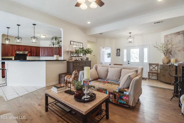 living area with visible vents, light wood-style flooring, recessed lighting, ceiling fan, and crown molding