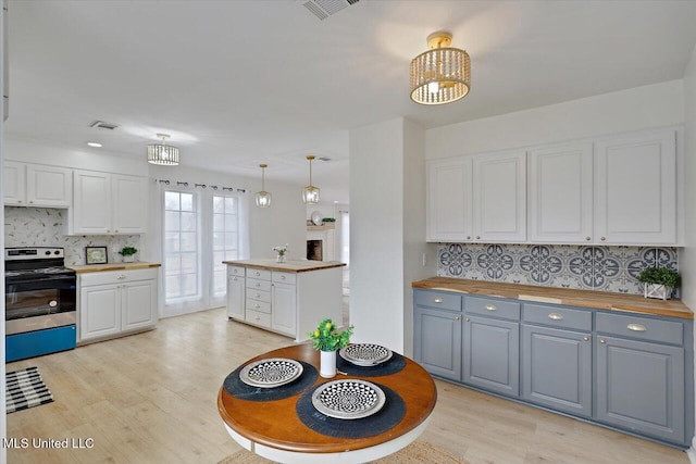 1505 Rosemont Dr, Clinton, MS 39056 - kitchen with stainless steel electric range oven, wood counters, light wood-style floors, and white cabinetry