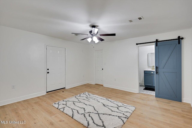 1505 Rosemont Dr, Clinton, MS 39056 - unfurnished bedroom with a barn door, light wood-type flooring, baseboards, and connected bathroom
