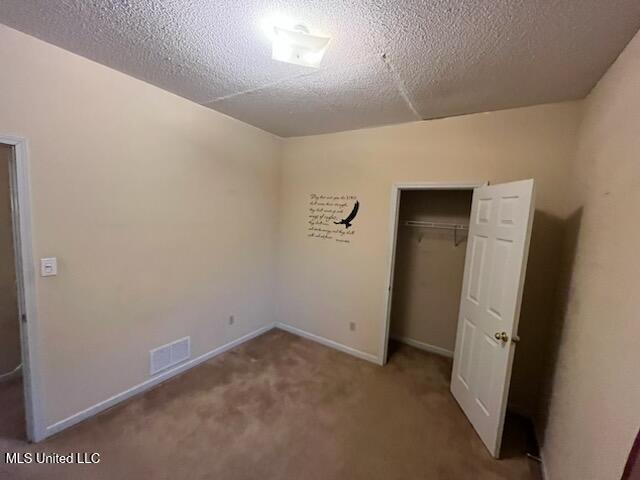 unfurnished bedroom with carpet flooring, a closet, and a textured ceiling