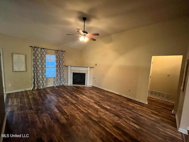 unfurnished living room featuring a tile fireplace, vaulted ceiling, dark hardwood / wood-style floors, and ceiling fan