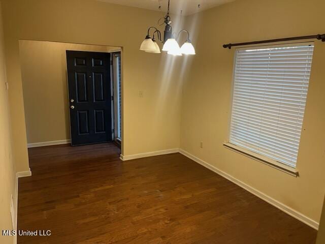 unfurnished dining area featuring an inviting chandelier and dark wood-type flooring