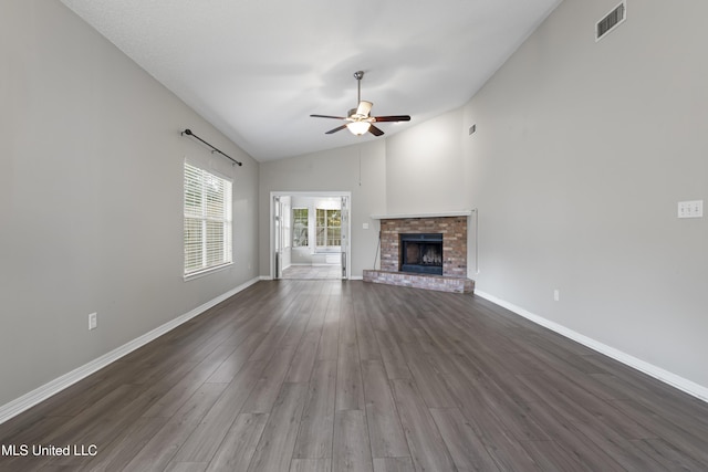 unfurnished living room with vaulted ceiling, ceiling fan, dark wood-style floors, baseboards, and a brick fireplace