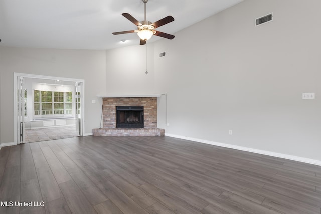 unfurnished living room featuring ceiling fan, dark wood finished floors, a brick fireplace, baseboards, and high vaulted ceiling