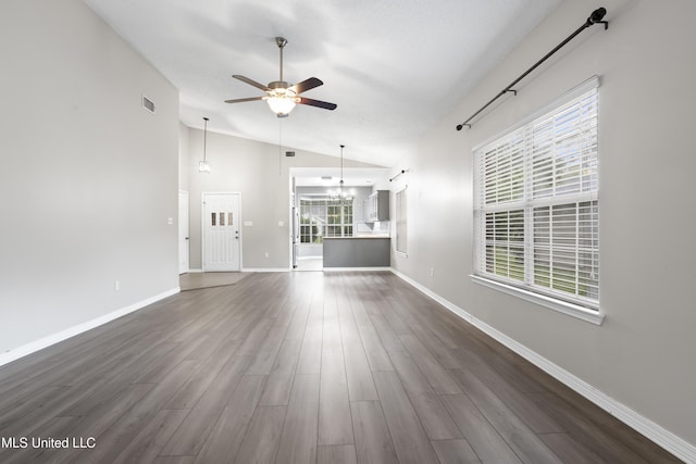 unfurnished living room with ceiling fan, vaulted ceiling, a chandelier, dark wood-style floors, and baseboards