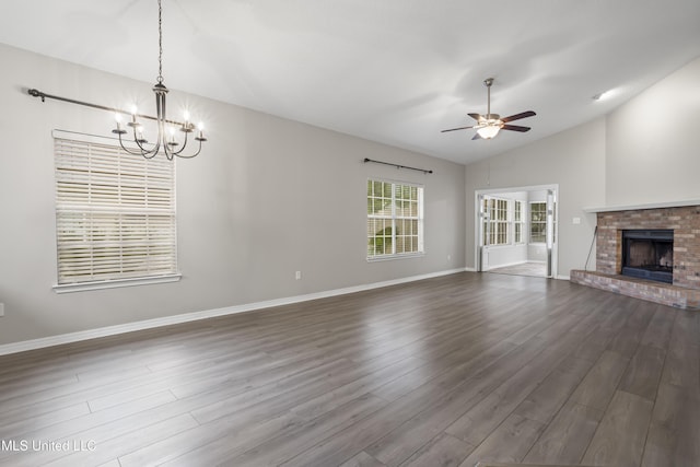unfurnished living room with vaulted ceiling, a ceiling fan, a chandelier, dark wood-style floors, and baseboards