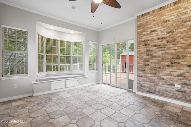 unfurnished sunroom featuring baseboards, a textured ceiling, brick wall, recessed lighting, and crown molding