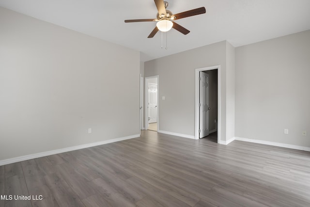 spare room featuring wood finished floors, a ceiling fan, and baseboards
