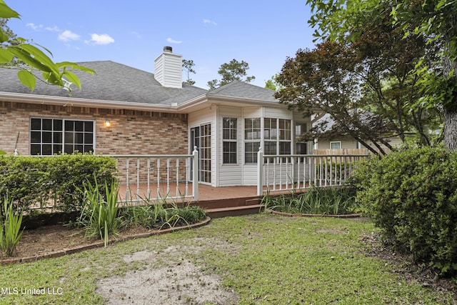 back of property featuring brick siding, a shingled roof, a deck, and a chimney
