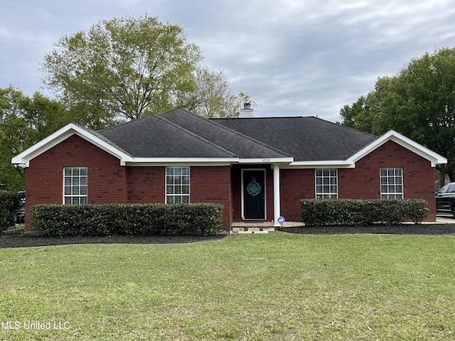 ranch-style home featuring a front lawn, roof with shingles, brick siding, and a chimney